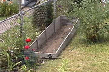 The raised flower bed half filled with soil.